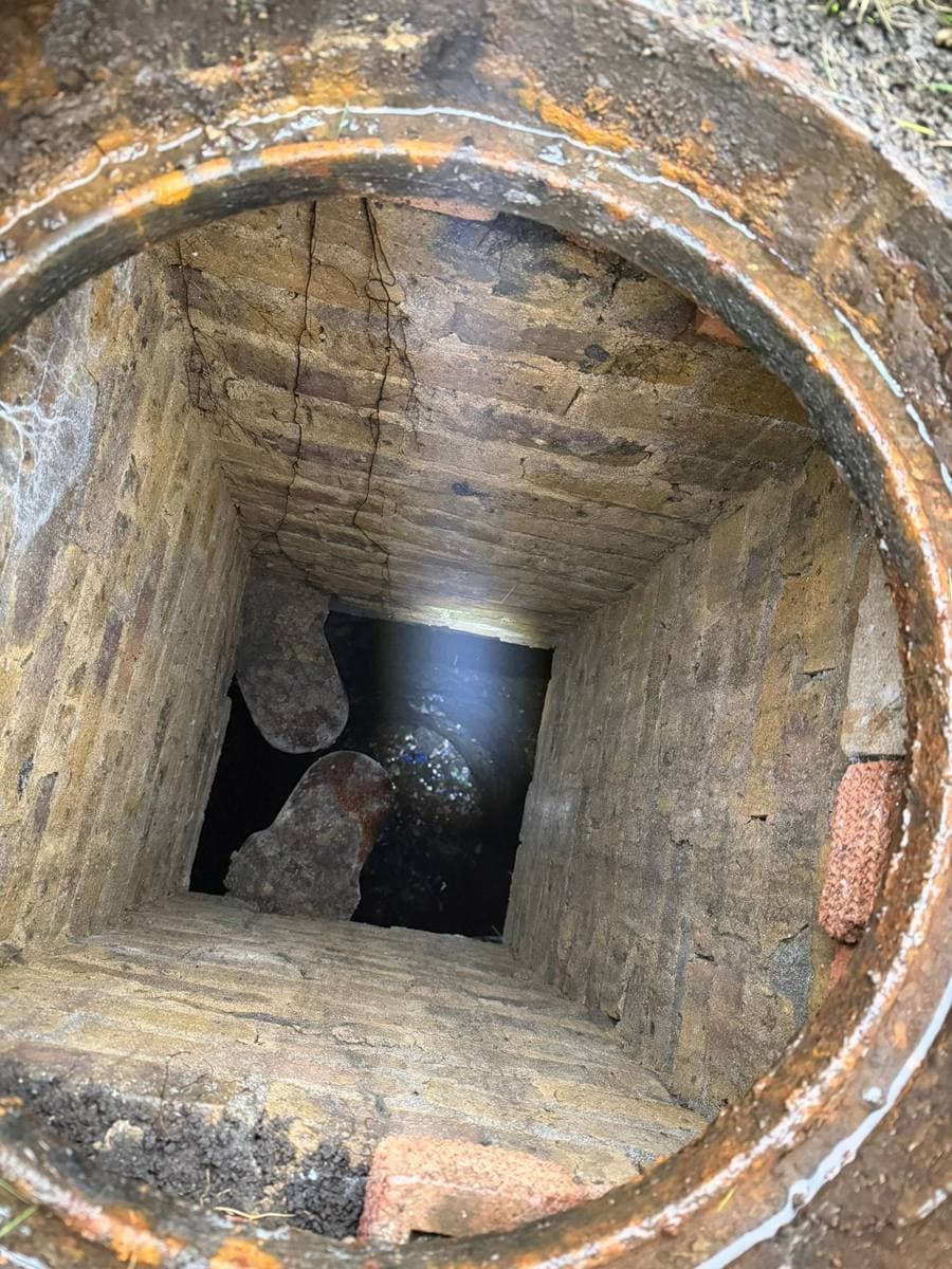 Opened brick drainage inspection chamber photographed during a site survey