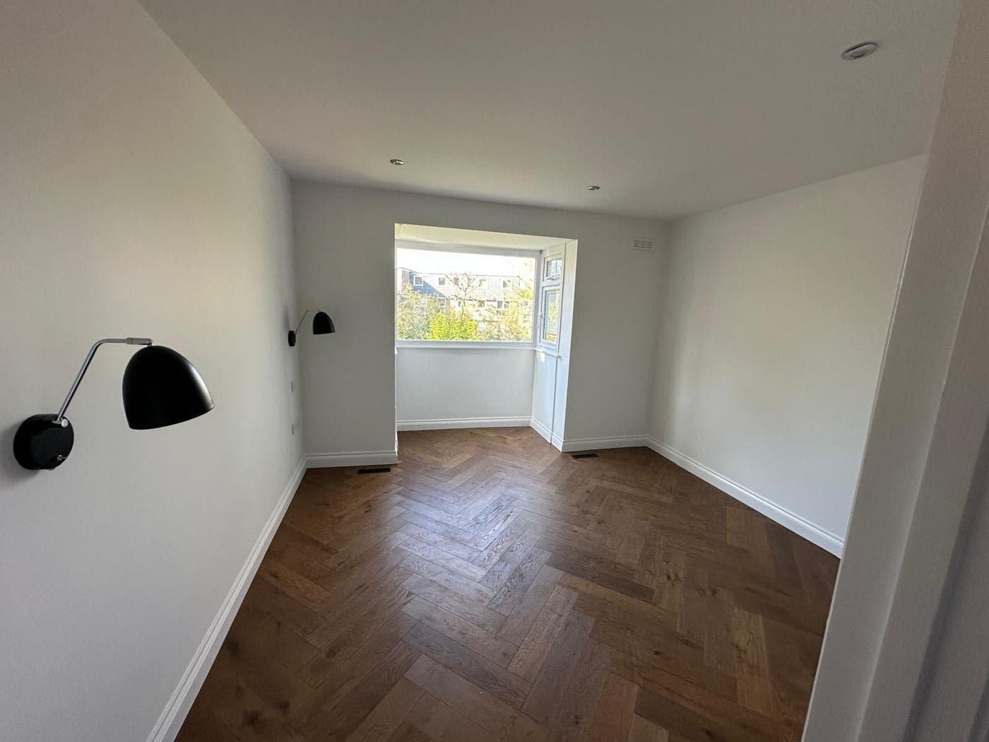 Refurbished bedroom with herringbone oak floor and wall lights — rcbGroup project